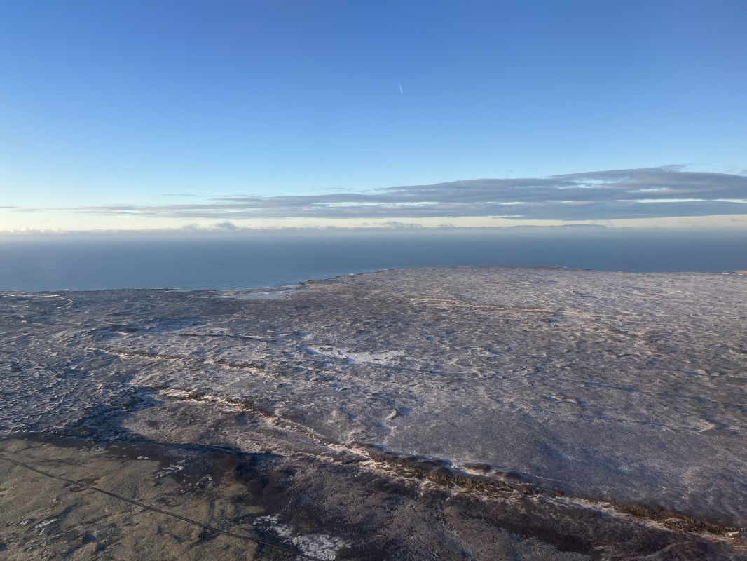 a landscape with a body of water and a snowy area