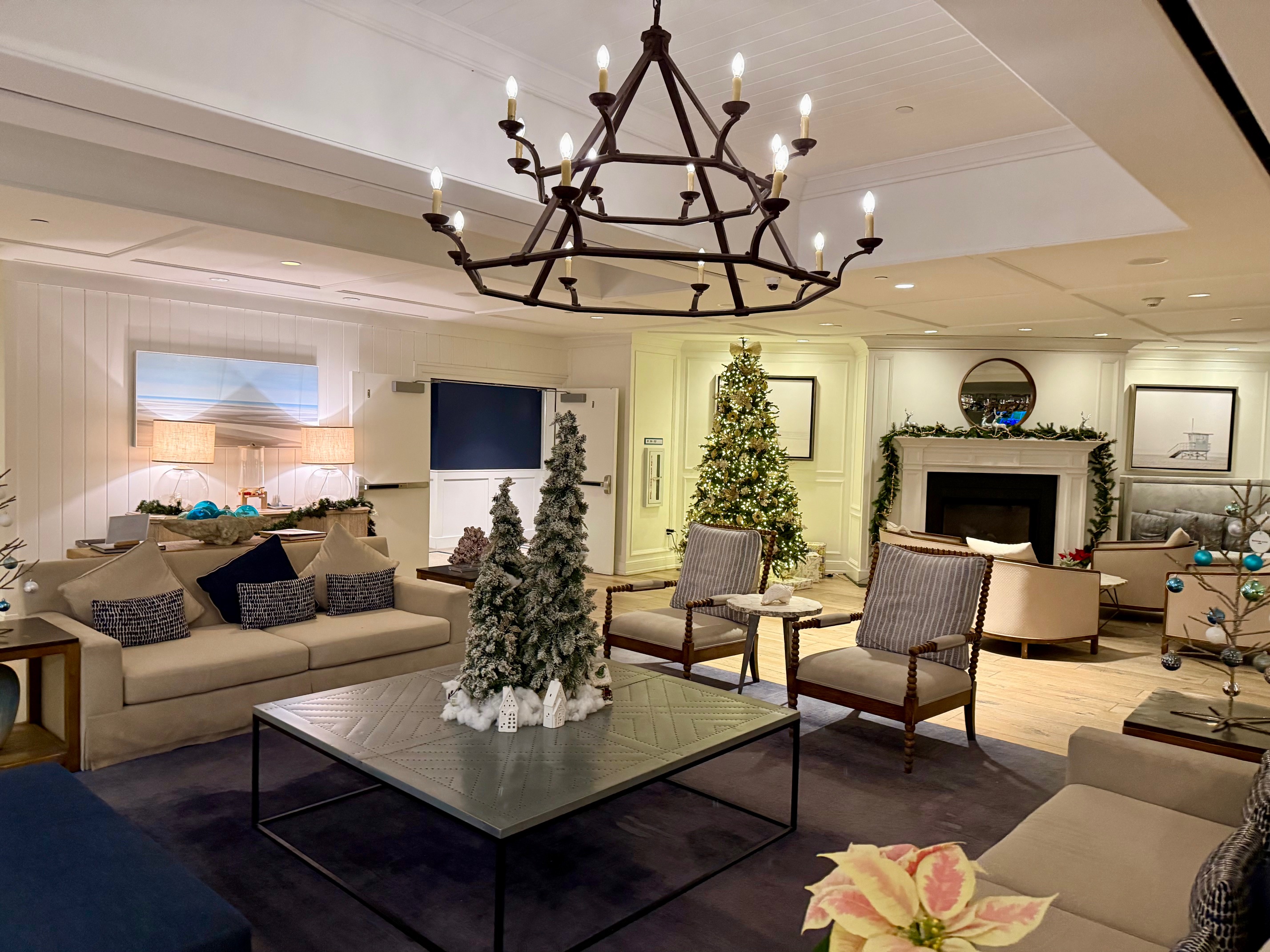 a room with a chandelier and christmas trees