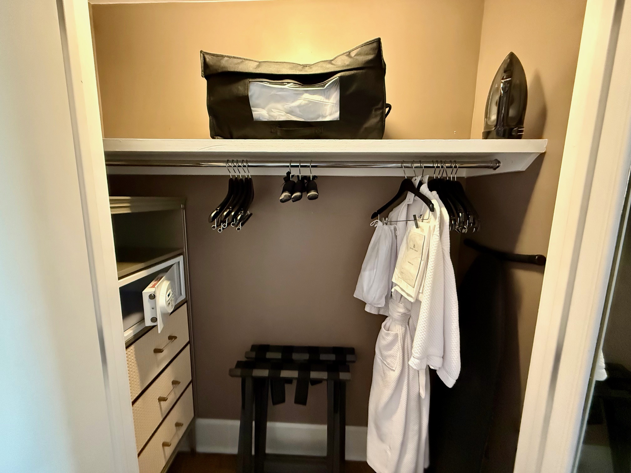 a closet with a white robe and a bag on top