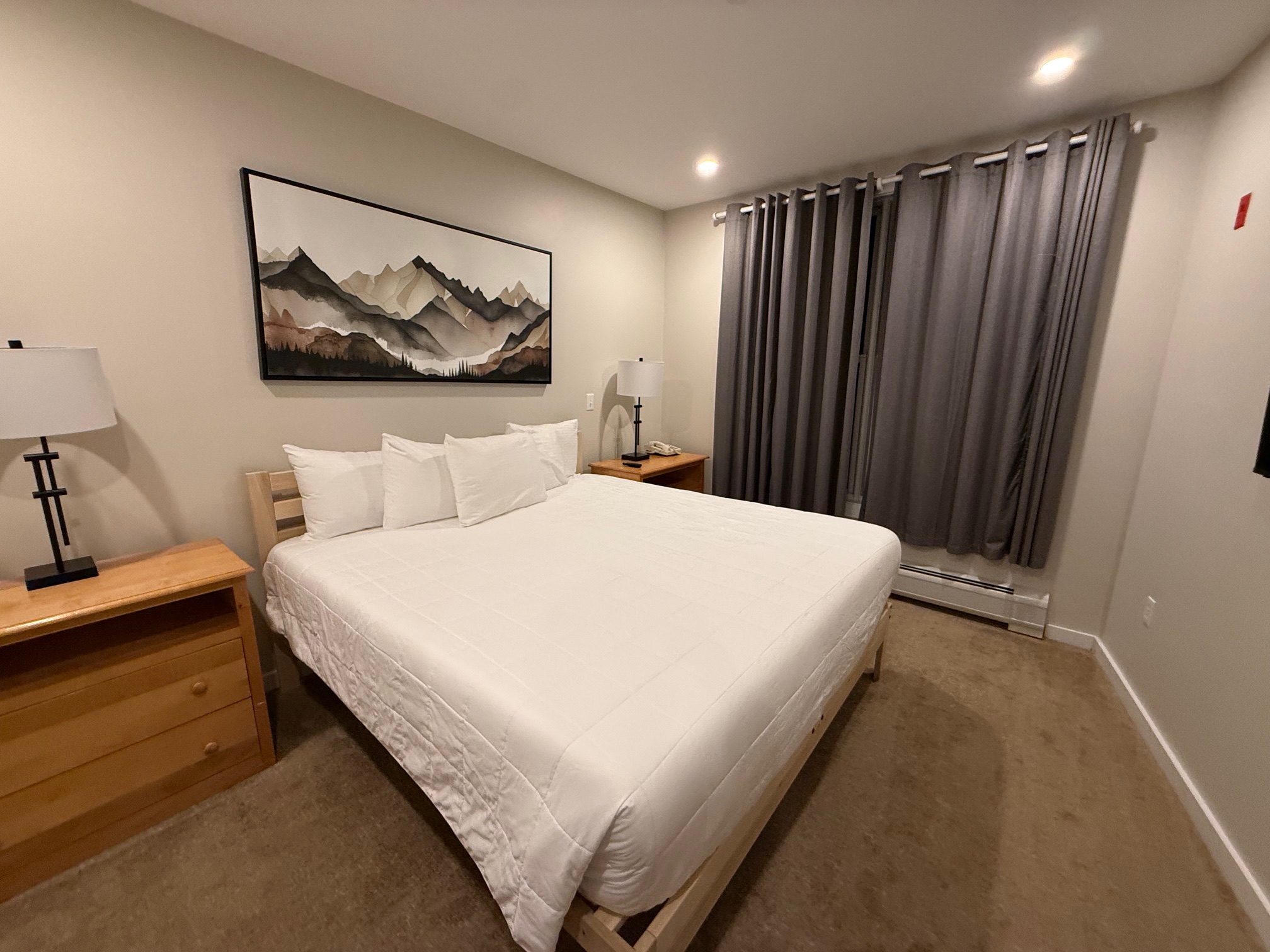 a bed with a white bedding and a painting on the wall at the Long Trail House Stratton