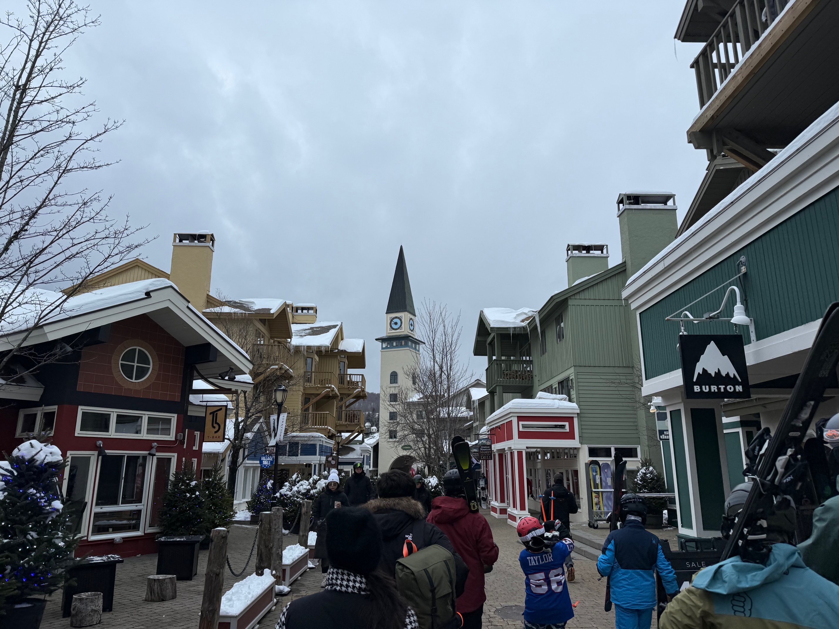 a group of people walking down a street with buildings and a tower