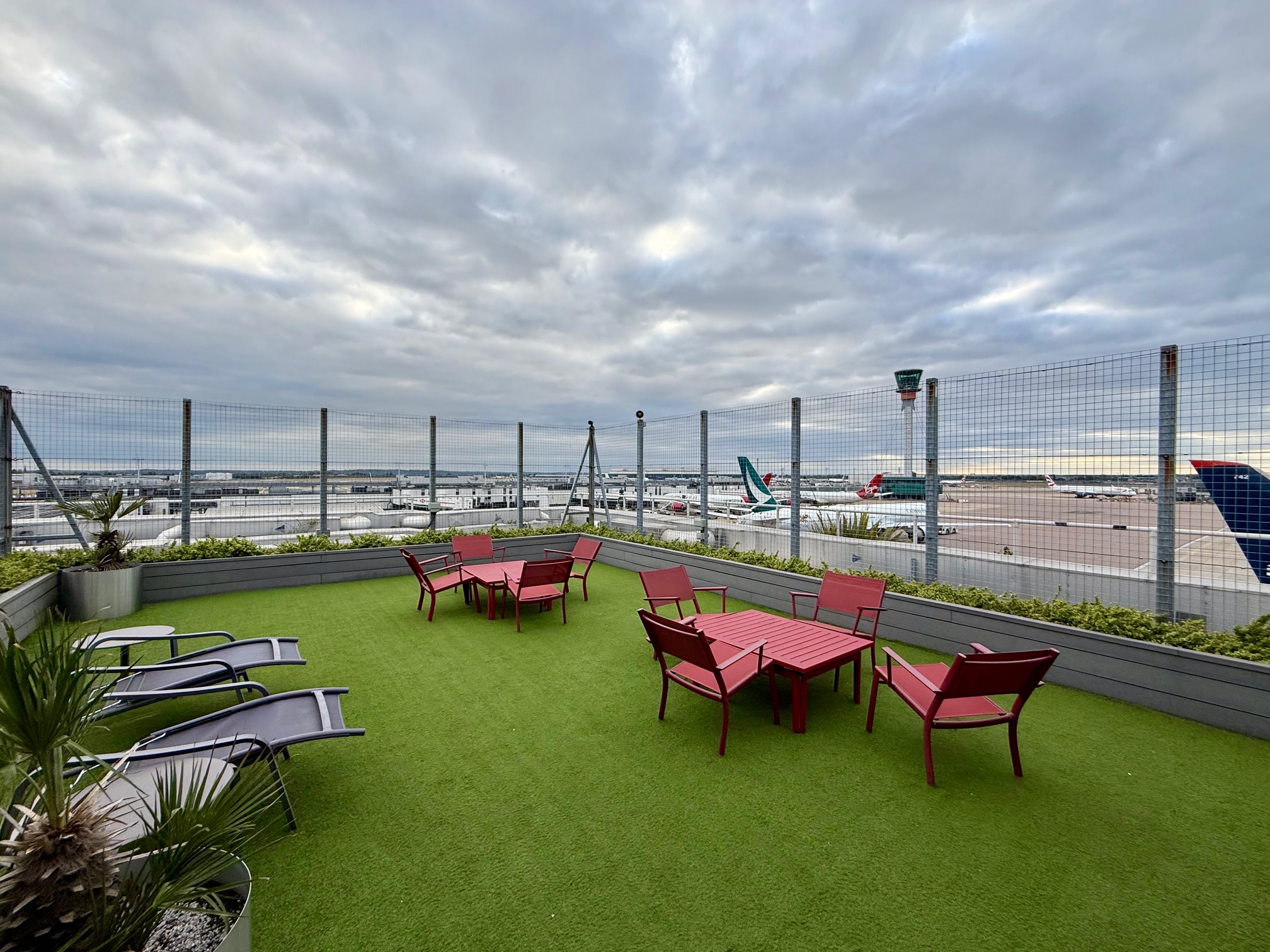 a patio area with chairs and tables on a green lawn at the Virgin Atlantic Clubhouse London