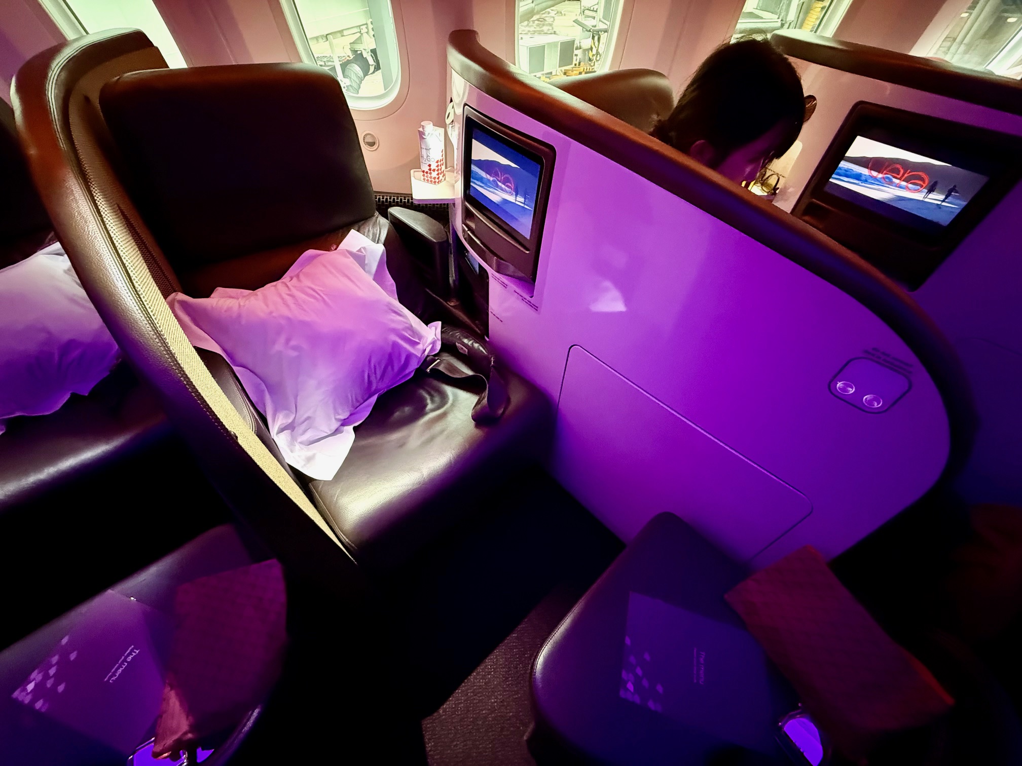 a person sitting in a chair with a pillow and a pillow on the back of a seat