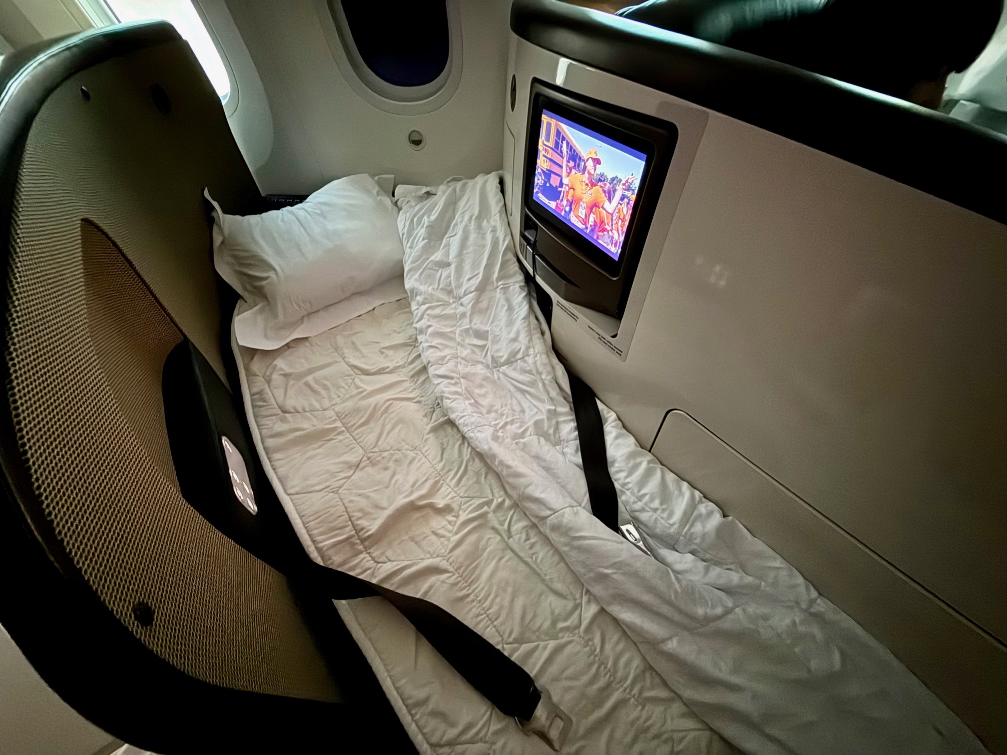 a bed with a pillow and a tv on the Virgin Atlantic 787-9 Upper Class