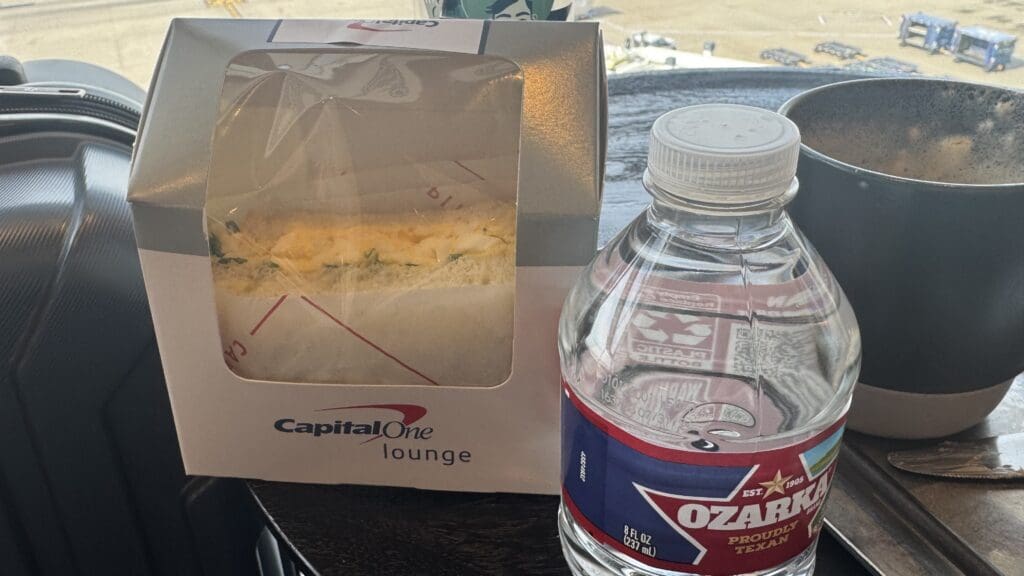a sandwich in a box next to a bottle of water