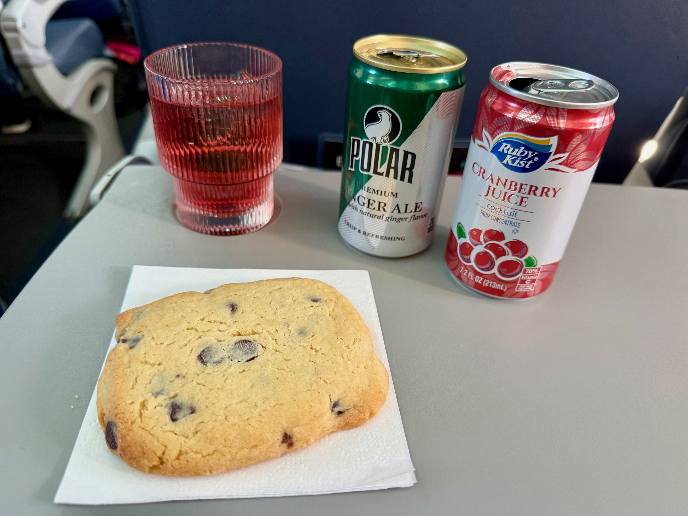 a cookie and two cans of soda on a table on BermudAir E175 Economy Cabin