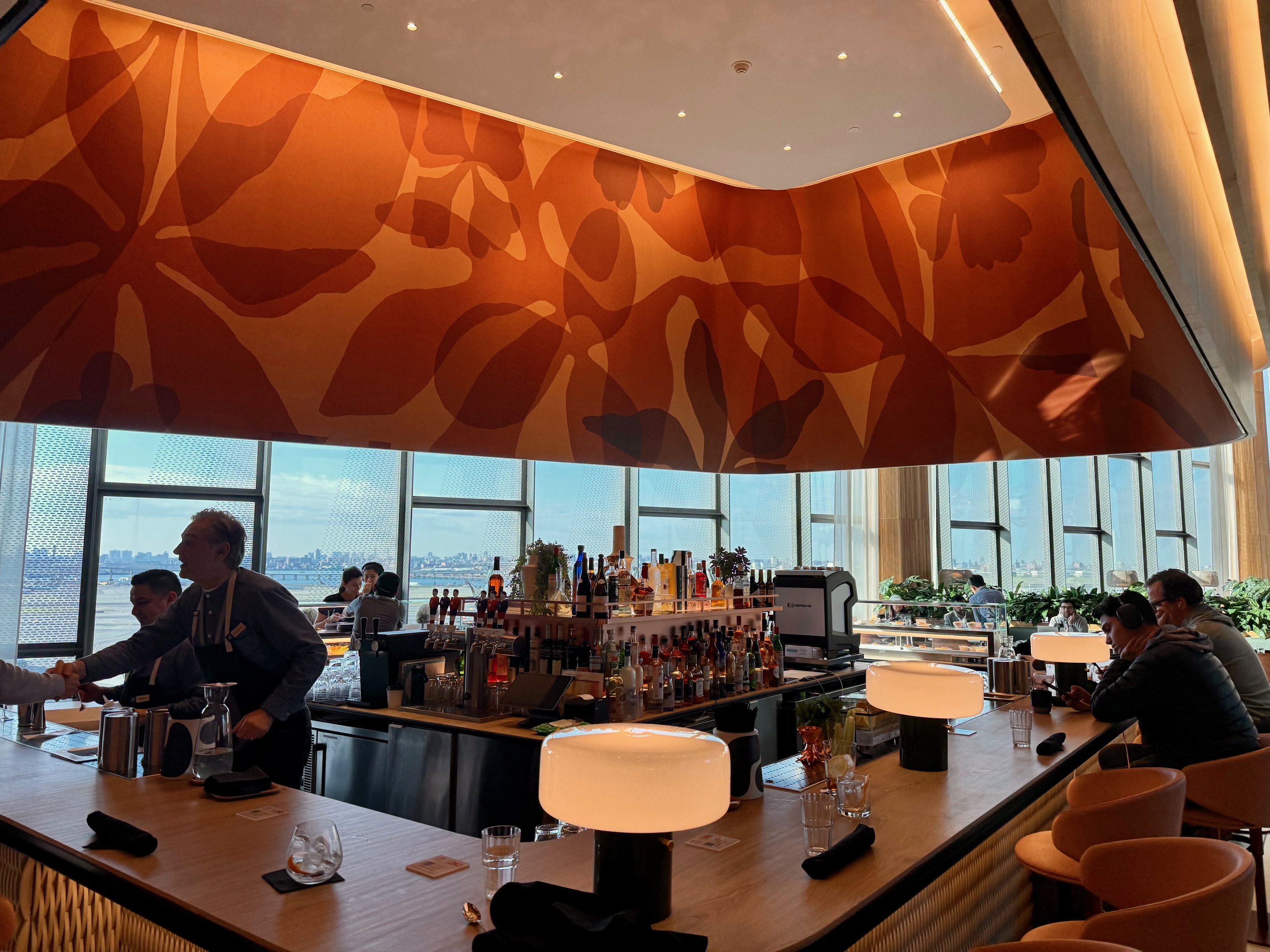 a bar with a couple of people sitting at the counter at the Capital One Landing at LaGuardia