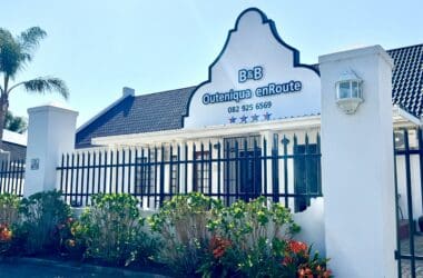a white building with a fence and flowers