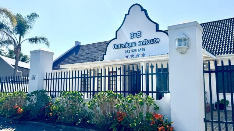 a white building with a fence and flowers
