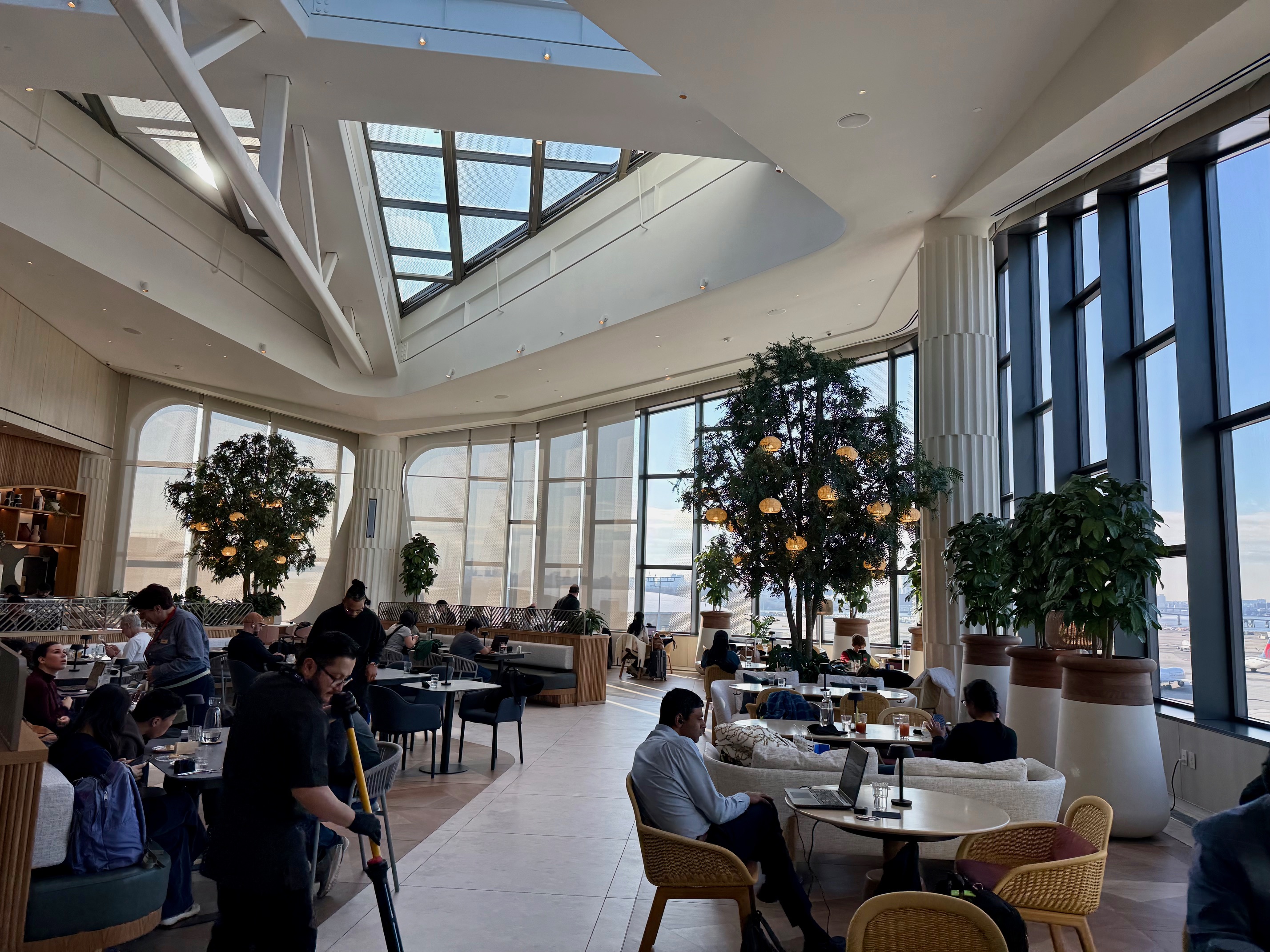 a room with many tables and chairs and a large skylight at the Capital One Landing at LaGuardia