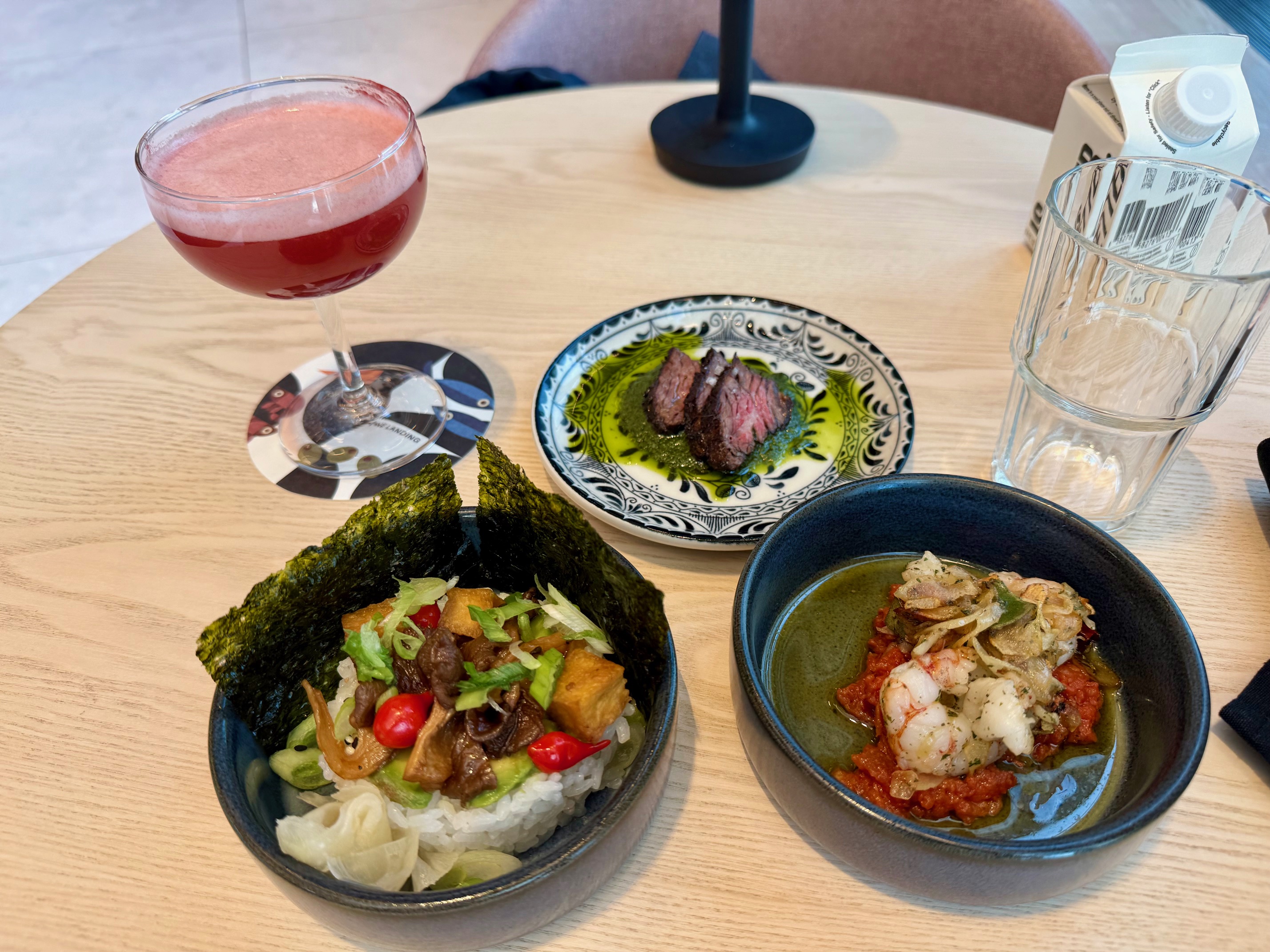 a table with plates of food and a drink at the Capital One Landing at LaGuardia