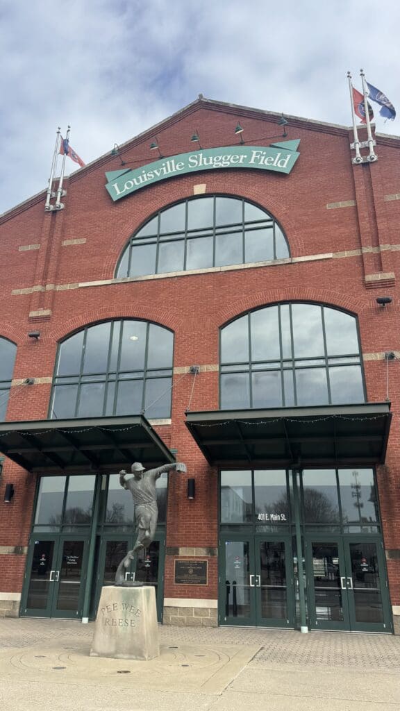 a statue of a baseball player outside of a brick building with Japanese American National Museum in the background