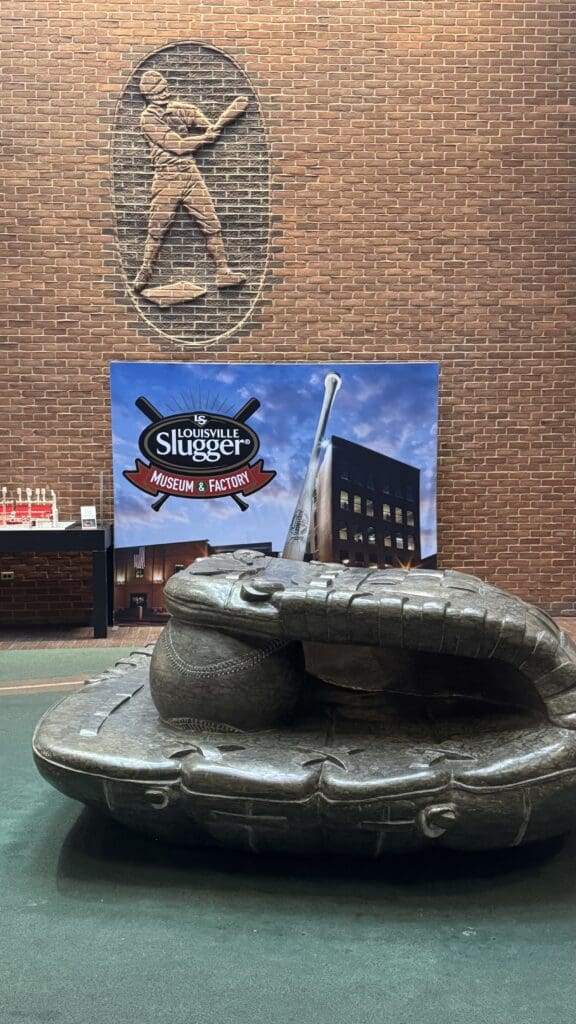 a statue of a baseball glove in front of a brick wall