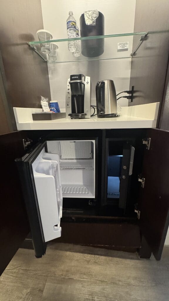 a small refrigerator with a coffee maker and a coffee pot on top