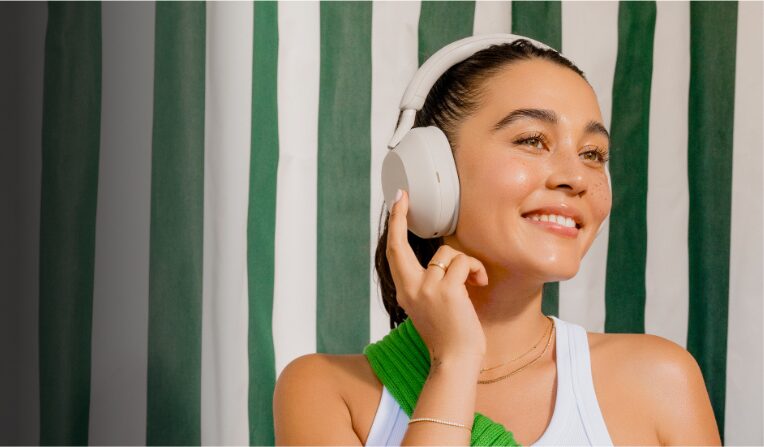 A young woman wearing a pair of Sony WH-1000XM5 Premium Wireless Noise Canceling Headphones which are currently on sale up to 38% off.