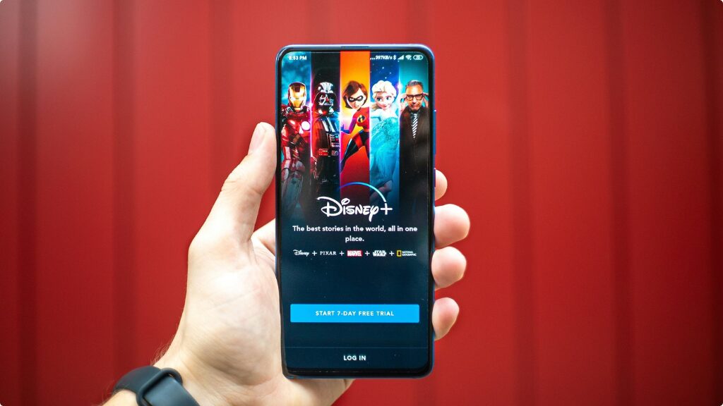 A person holding a mobile phone displaying the Disney+ mobile app